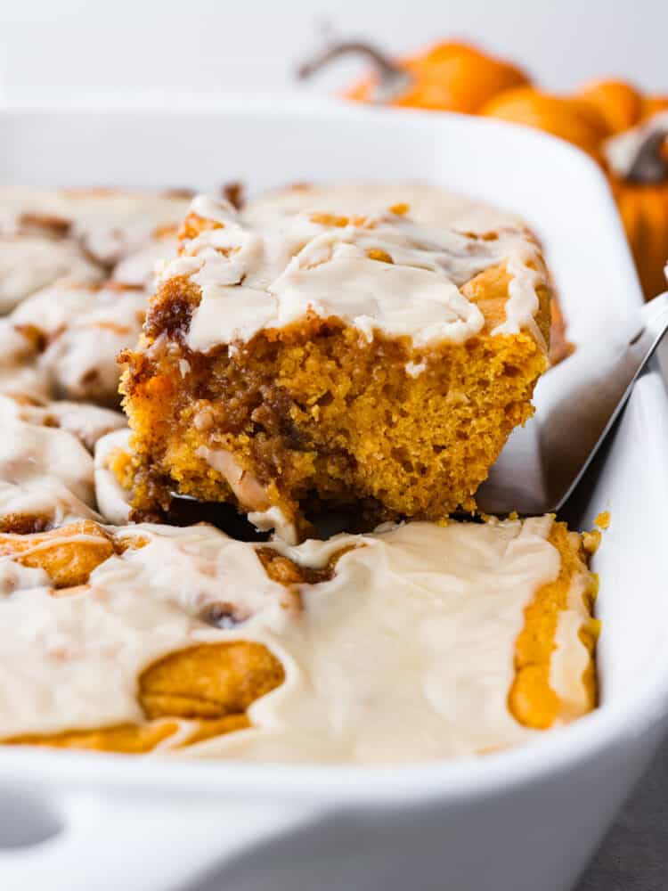 Pumpkin cinnamon roll cake in a 9x13 dish being served with a pie server. 