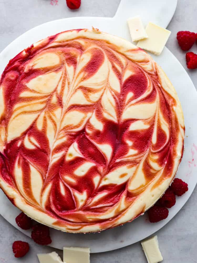 The top view of a white chocolate raspberry cheesecake on a platter. 