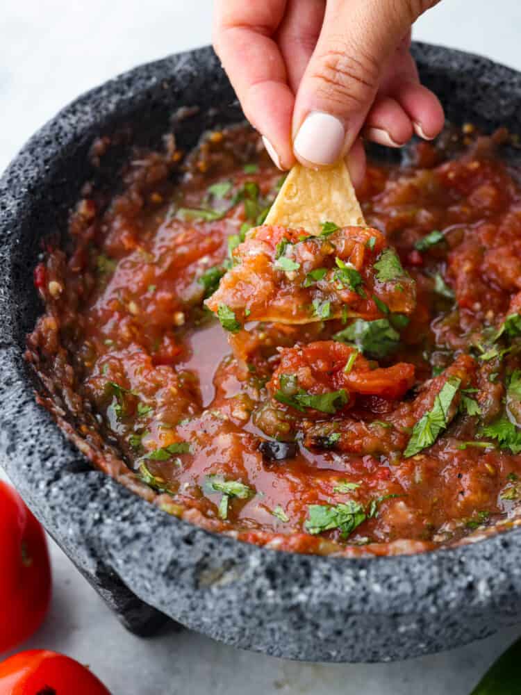 Closeup of a chip being dipped in roasted tomato salsa.