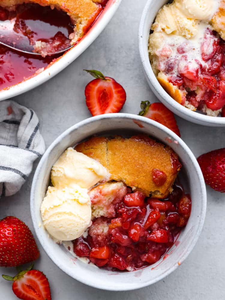 The top view of strawberry cobbler in a bowl with a scoop of vanilla ice cream. 