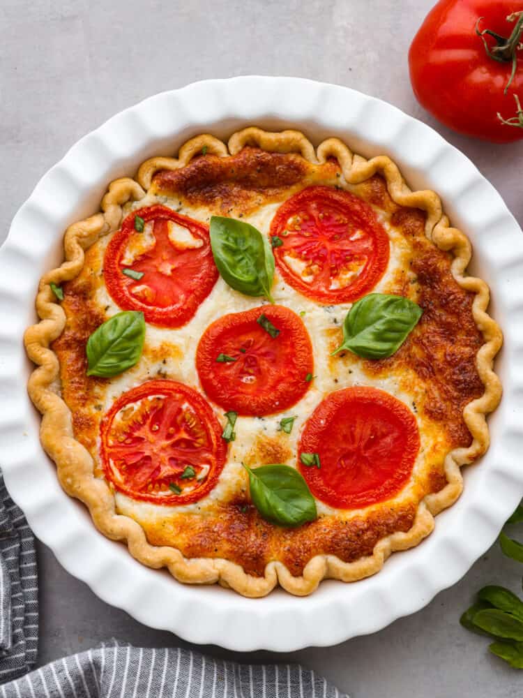 The top view of a tomato pie in a white pie pan. 