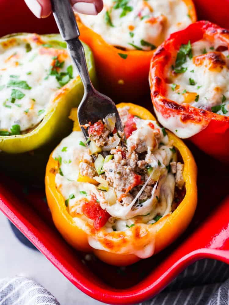 A fork sticking into a pepper filled with ground turkey, melted cheese, and herbs.