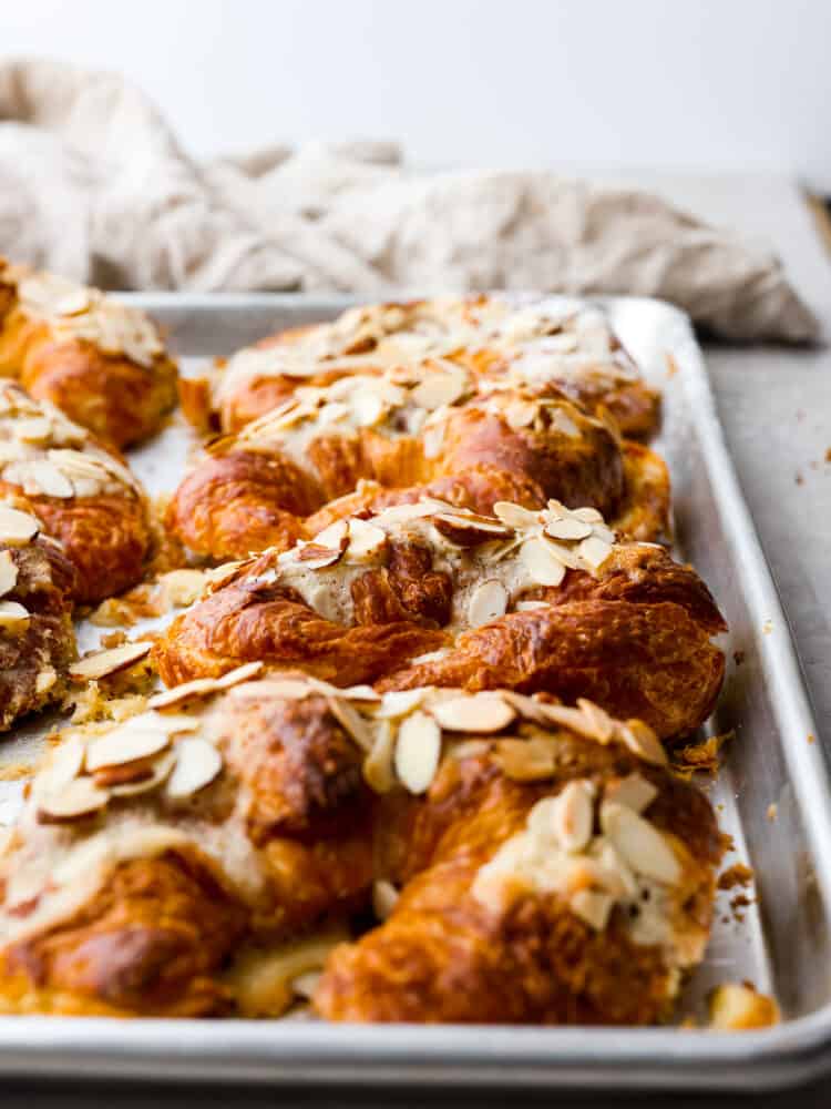 Croissants lined up on a baking sheet.