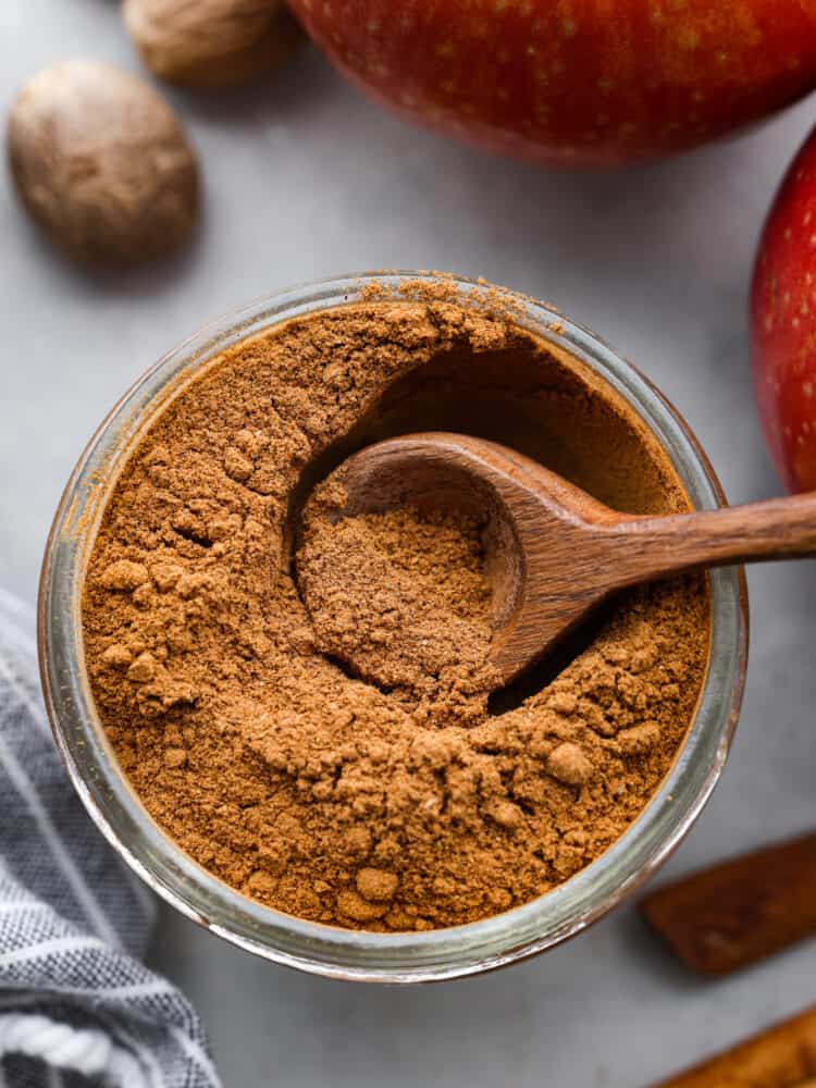 The top view of apple pie spice in a jar with a wooden spoon. 