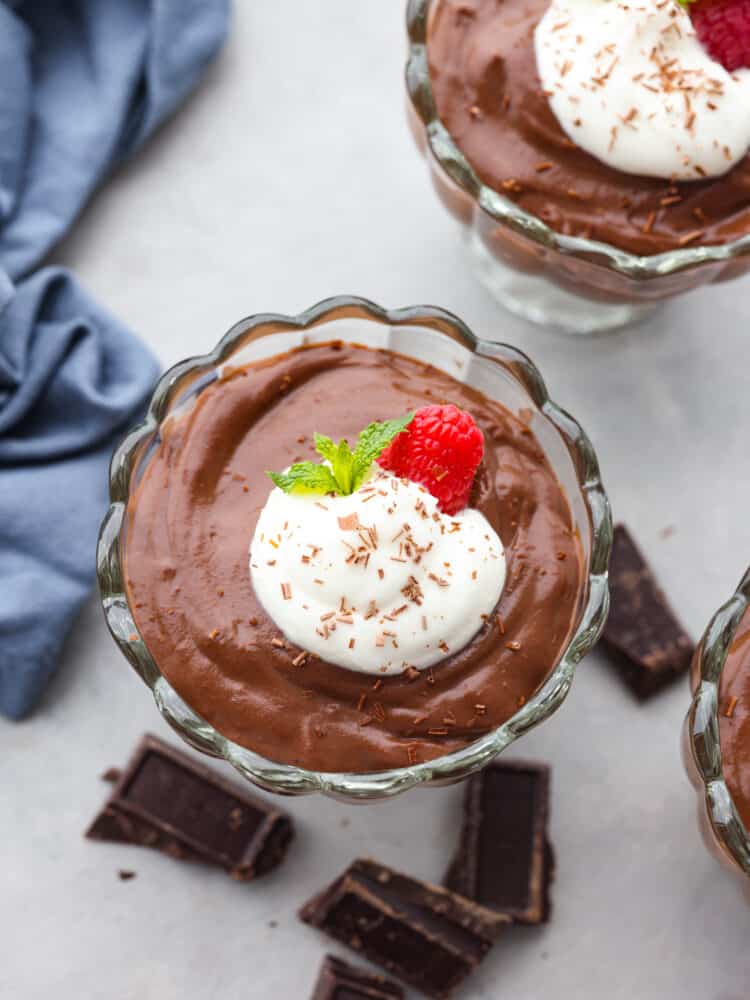 Top-down view of chocolate pudding in a glass jar, garnished with whipped cream and a berry.