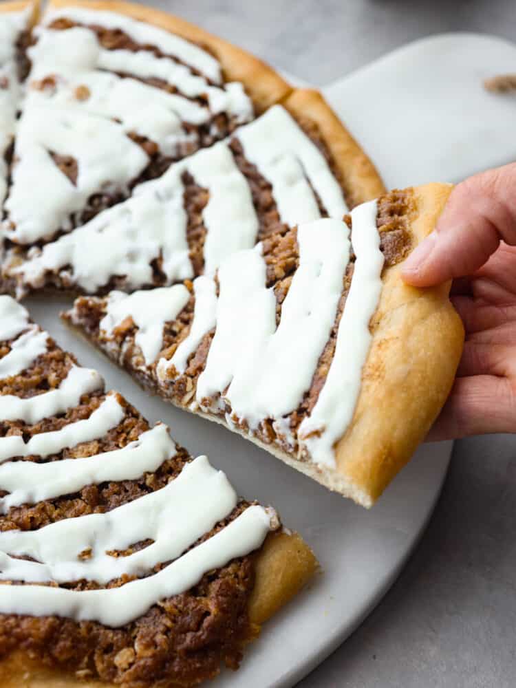 A slice of dessert pizza being taken off of the platter. 