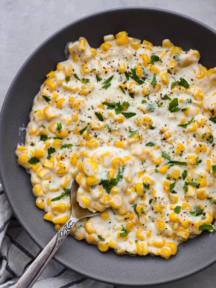 Top-down view of creamed corn in a black bowl, ready to serve.