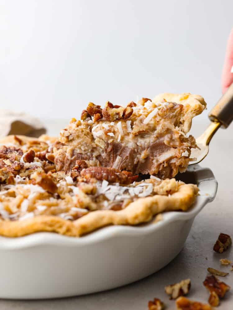 A slice of German chocolate pie being served with a cake spatula.