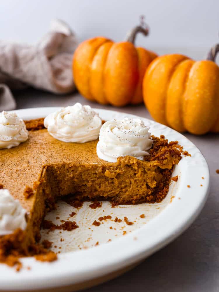 Dessert with a few slices taken out with pumpkins in the background.