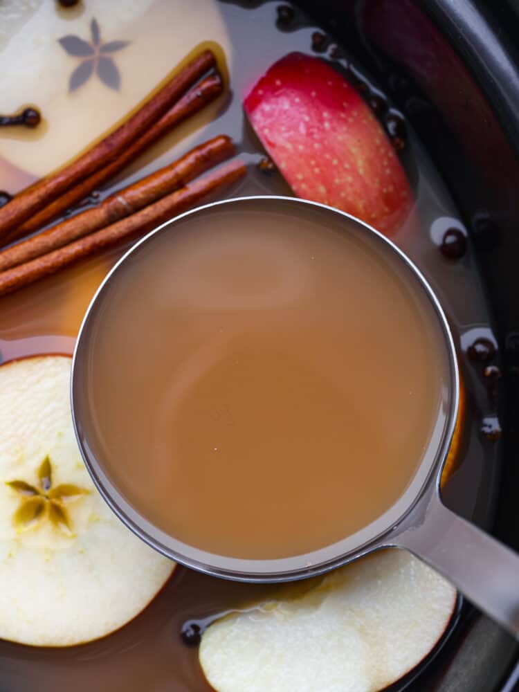 A measuring cup filled with apple cider. 