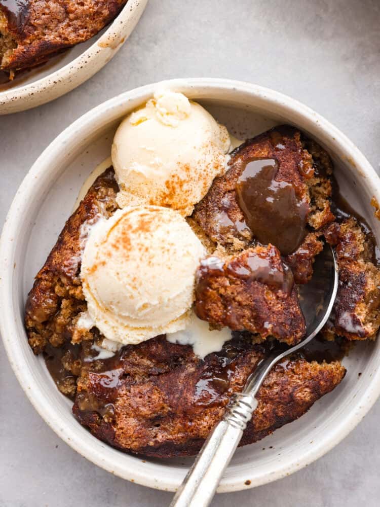 The topview of a bowl of snickerdoodle cobbler with 2 scoops of vanilla ice cream on top. 