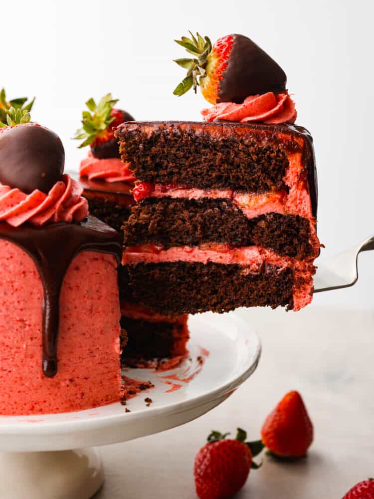 Side photo of a slice of strawberry chocolate cake being lifted off the cake platter.