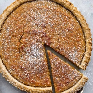 Treacle tart with a slice being lifted out of the tart with a pie scoop.