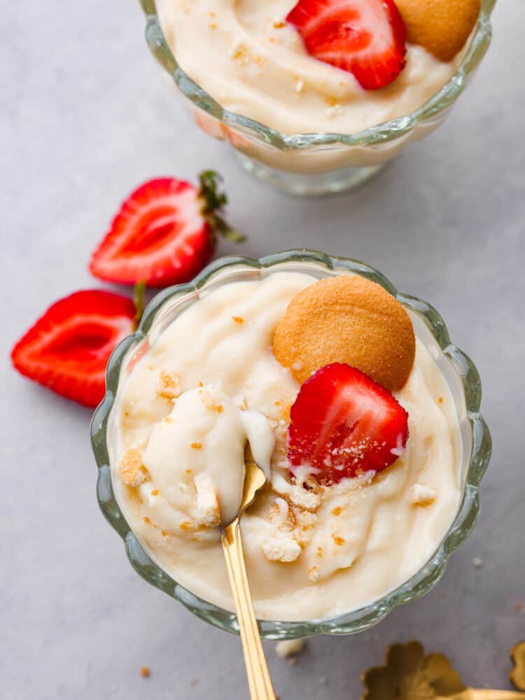 Top-down view of vanilla pudding in a glass cup, garnished with a sliced strawberry and Nilla Wafer.