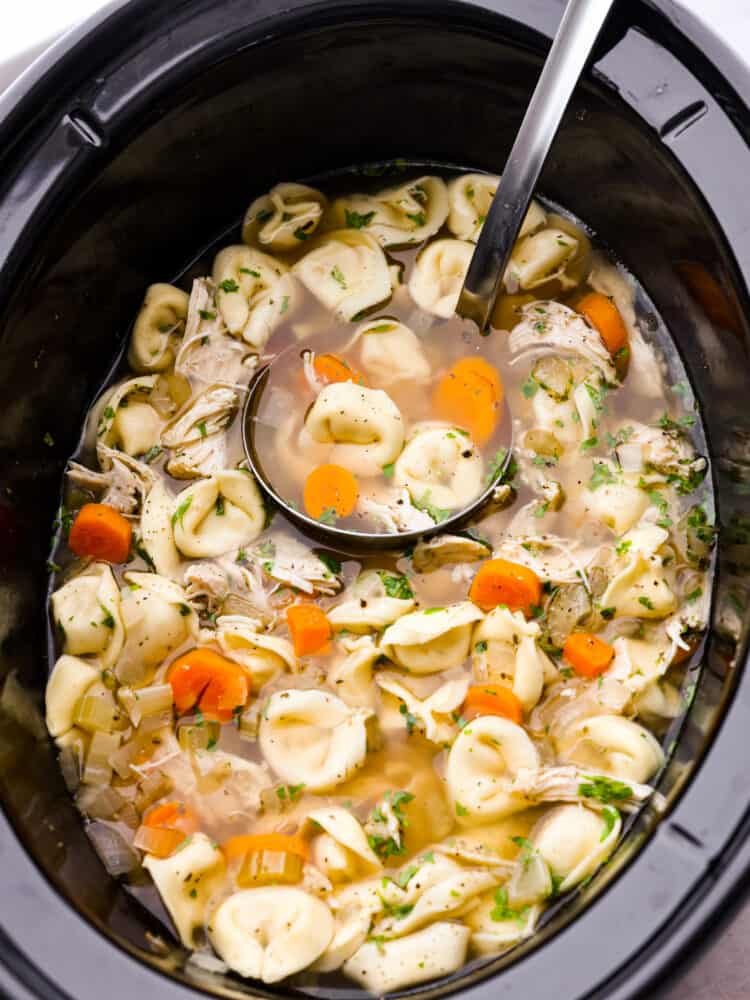 The top view of soup in a slow cooker with a label scooping some out. 