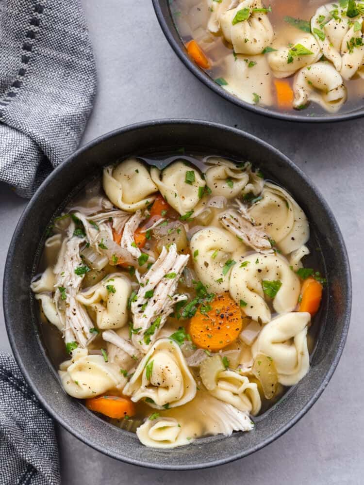 A gray bowl filled with chicken tortellini soup. 