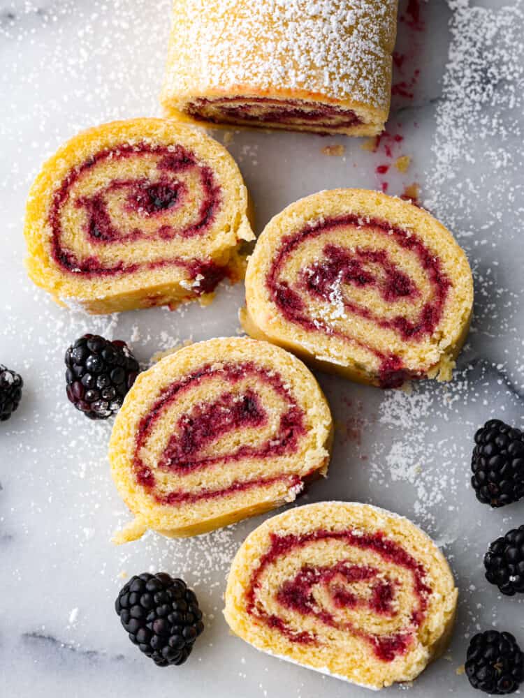 Jelly roll cake cut up an laid out on the counter with powdered sugar sprinkled on top.