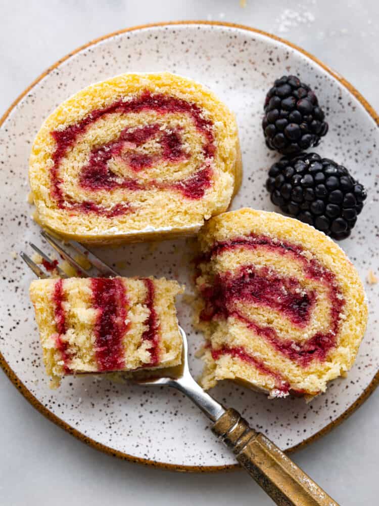 Pieces of cake on a plate with blackberries next to it.