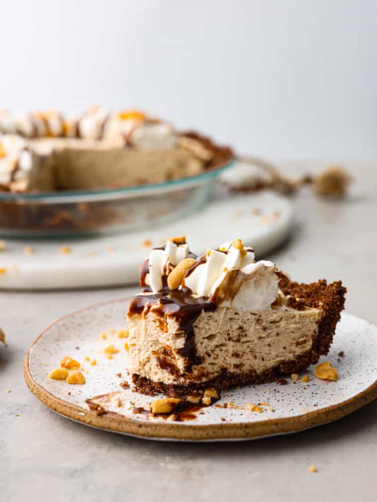 A slice of pie served on a stoneware plate, topped with chocolate drizzle.