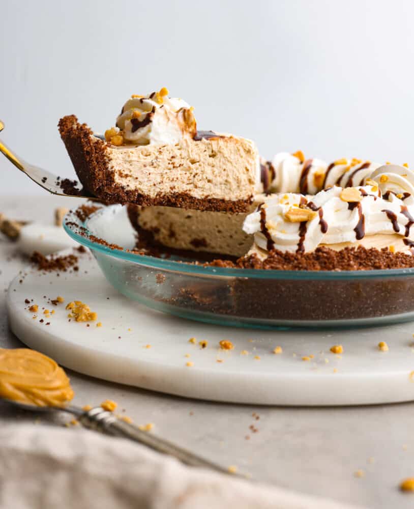 A slice of no-bake cream cheese peanut butter pie being served with a cake spatula.