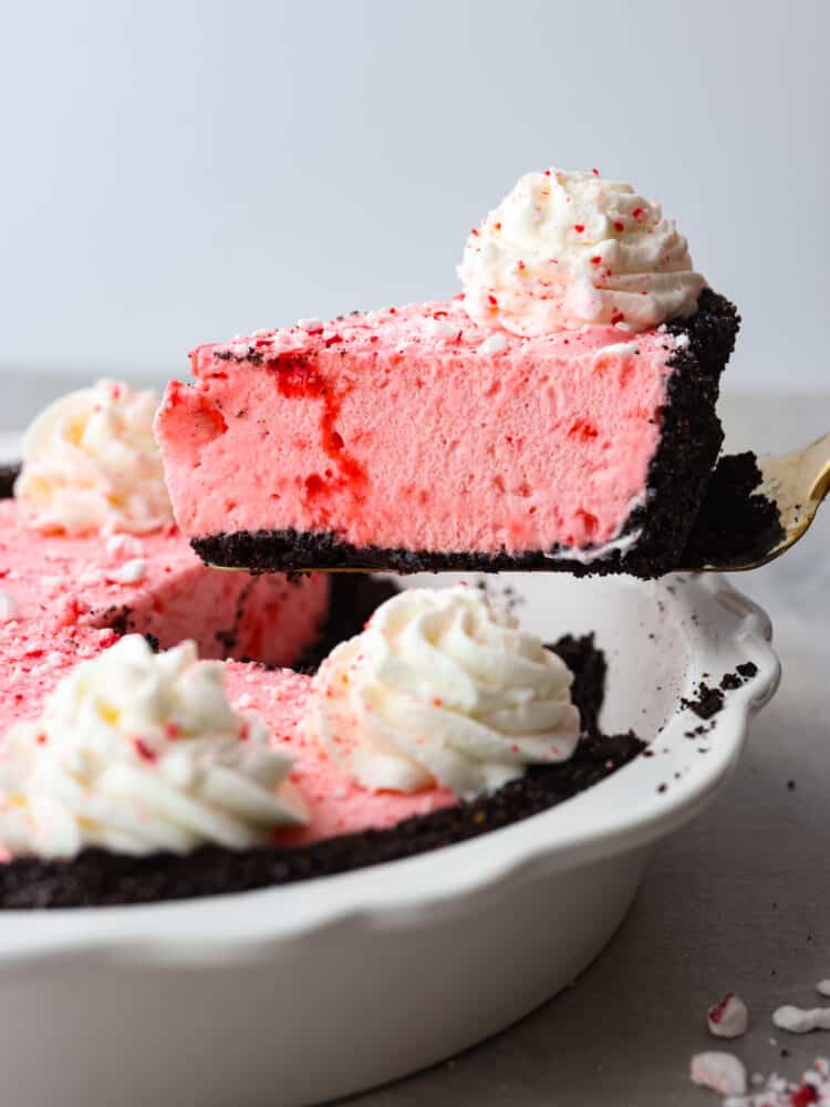 A slice of peppermint pie being served out of the pie dish with a gold pie server. 