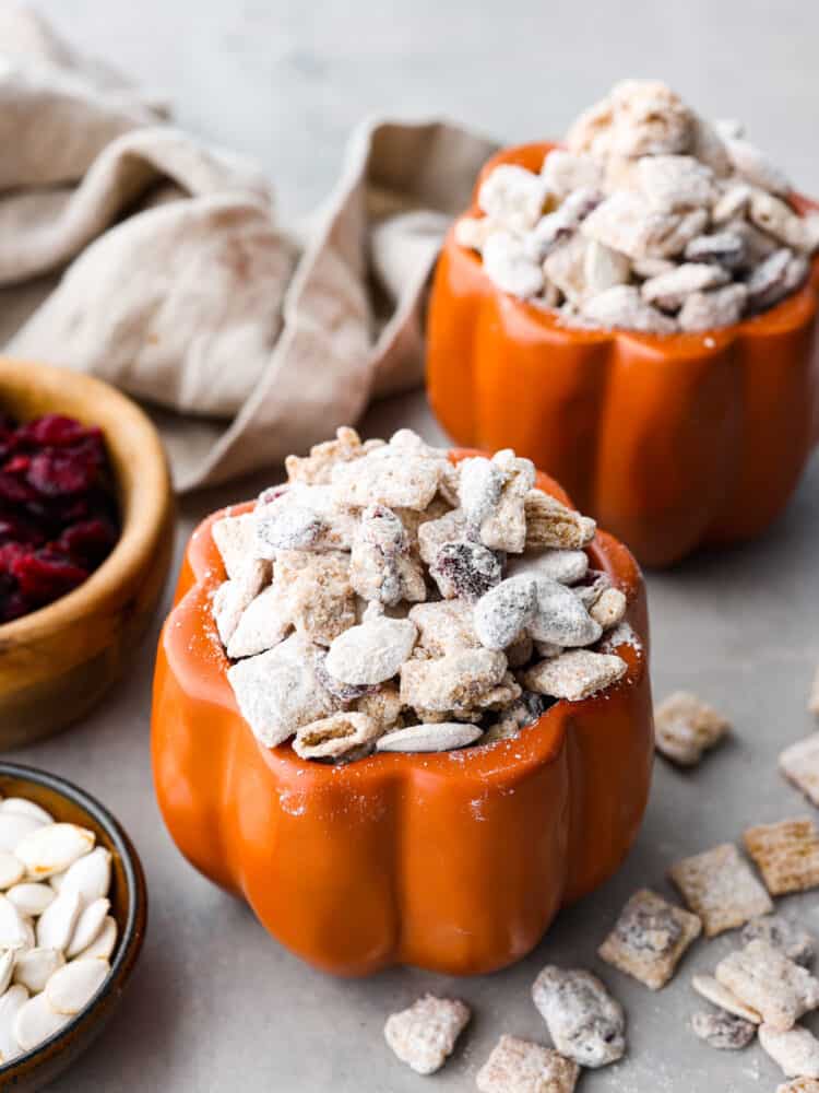 Pumpkin spice muddy buddies inside of a pumpkin-shaped jar.