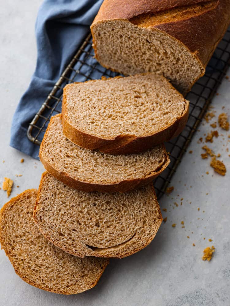 Sliced Sprouted Whole Wheat bread on a cooling rack with a blue tea towel underneath.