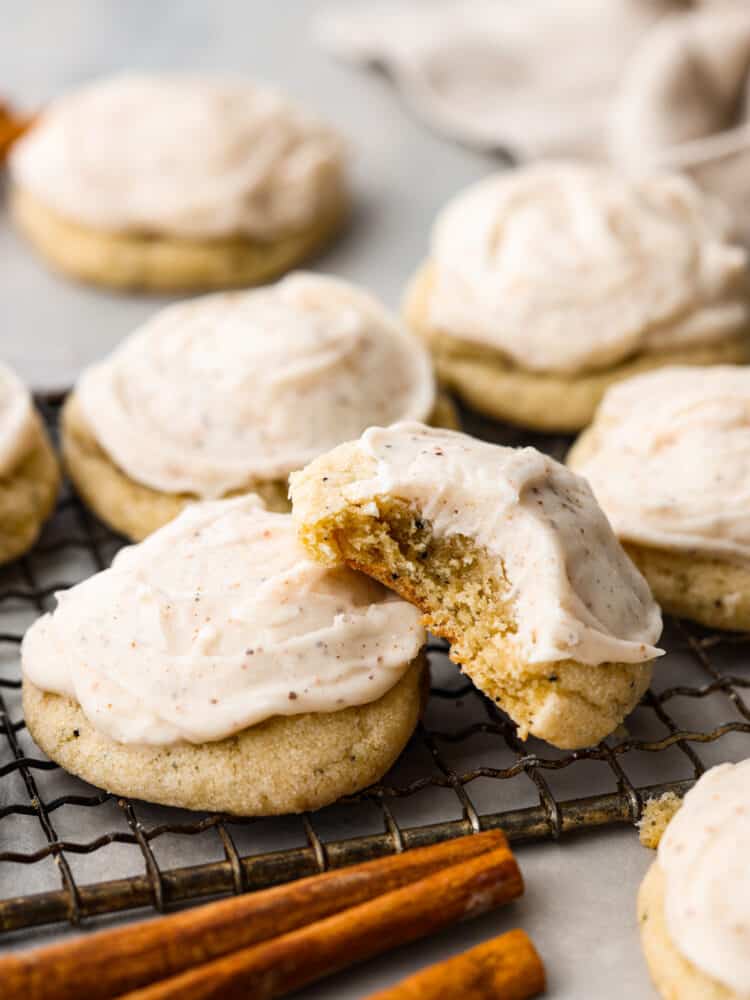 Taylor Swift Chai cookies sitting on a wire rack, one of them has a bite taken out of it.