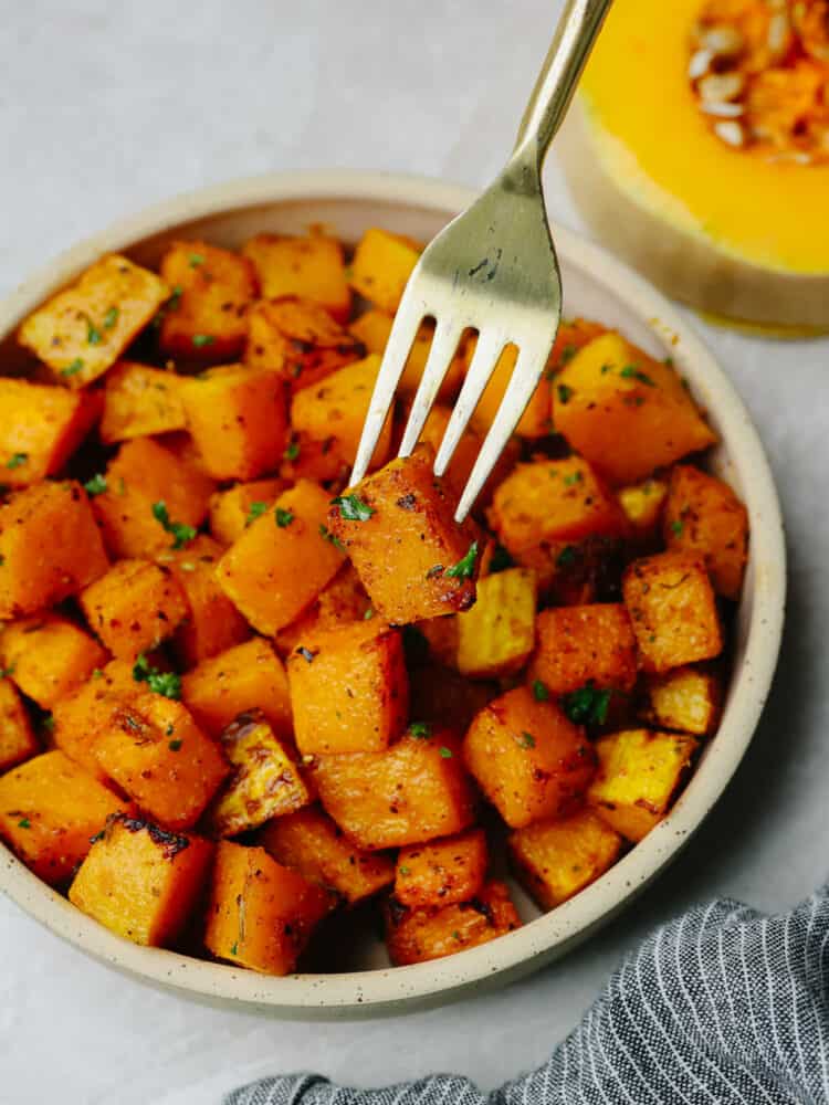 Close up photo of squash on a small tan colored plate with a fork lifting out a piece of squash.