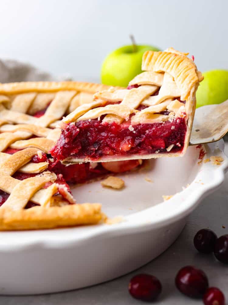 A slice of cranberry apple pie being served with a cake spatula.