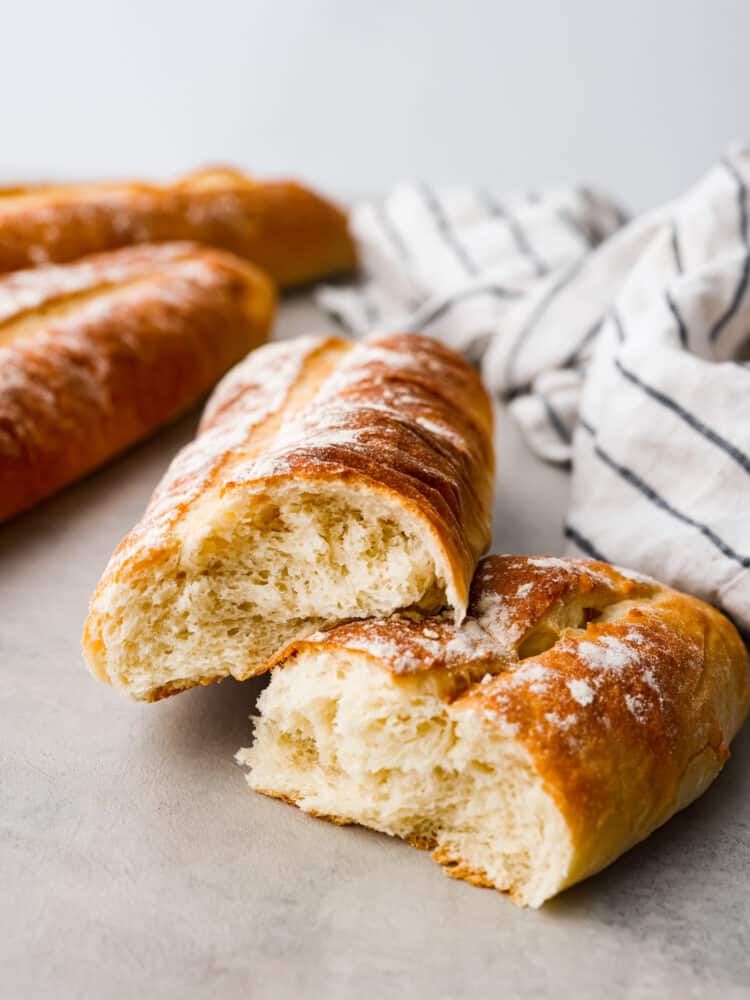 A loaf of bread ripped in half showing the inside with other loaves in the background.