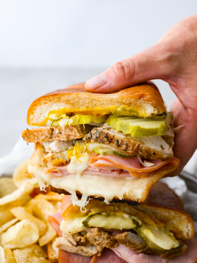 The close up of someone holding one half of a Cuban sandwich. 