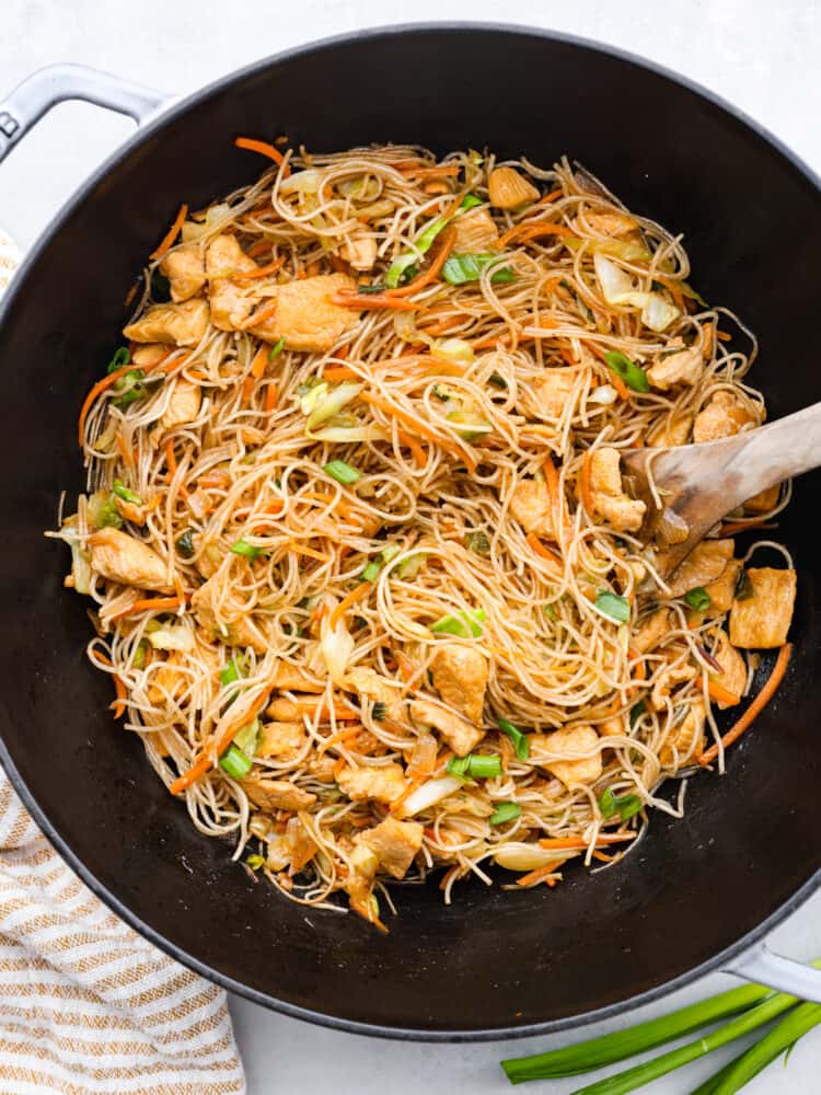 Panict in a large black wok with a wooden serving spoon in the wok.