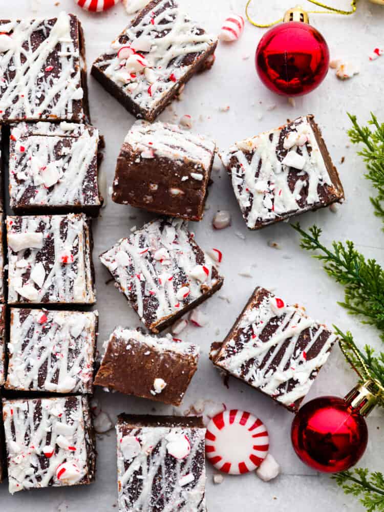 Chocolate peppermint fudge on parchment with a Christmas ornament and some greenery.