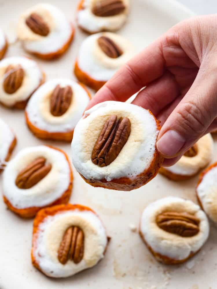 Close up view of a hand holding a sweet potato bite with the platter in the background.