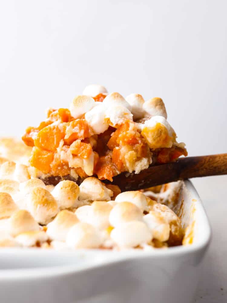 Sweet potato cobbler being scooped out of the pan with a wooden spoon.