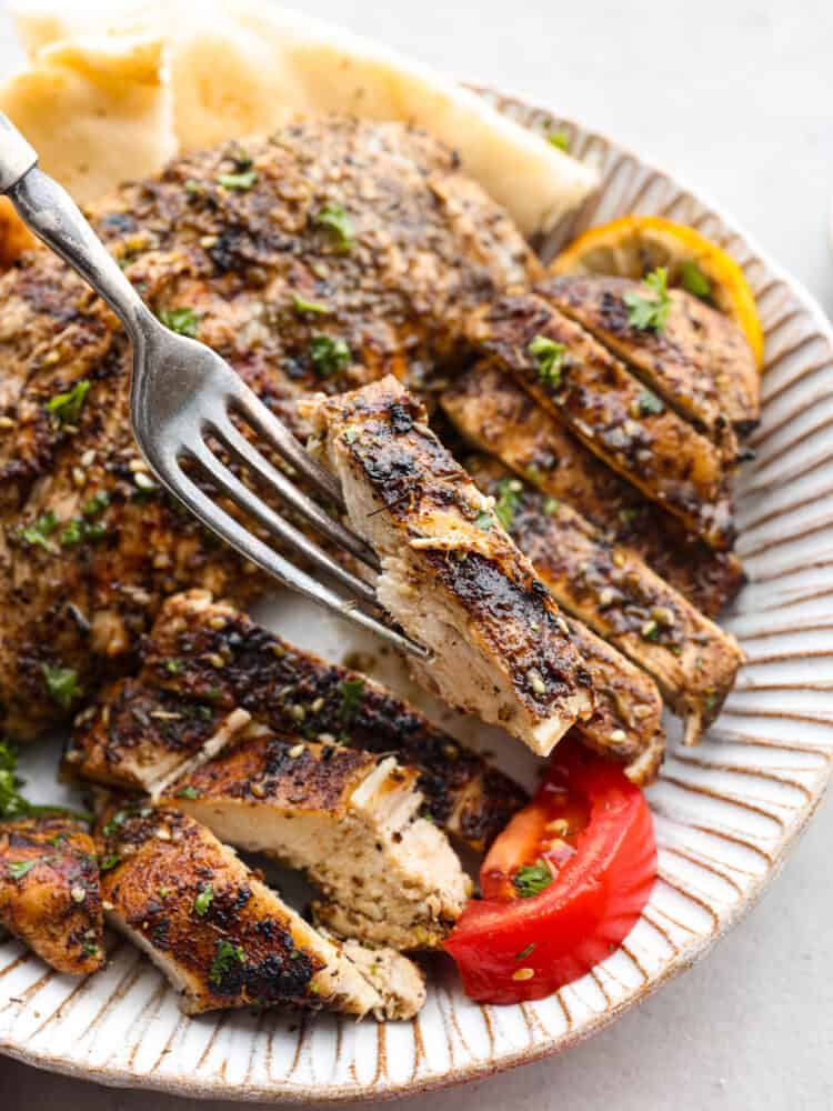 Chicken with grill marks sliced into strips with a fork holding up a piece of chicken.