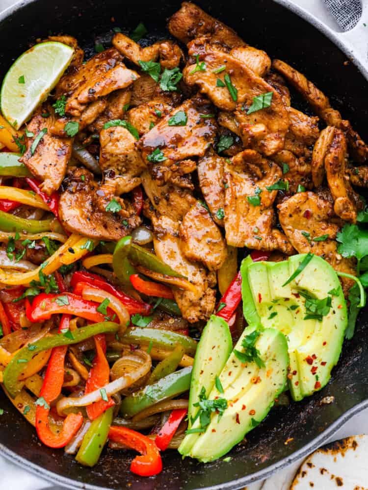 A close up on chicken fajitas with fresh avocado.