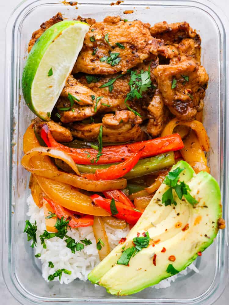 A close up on the chicken fajita meal prep bowl with a fresh lime and avocado.