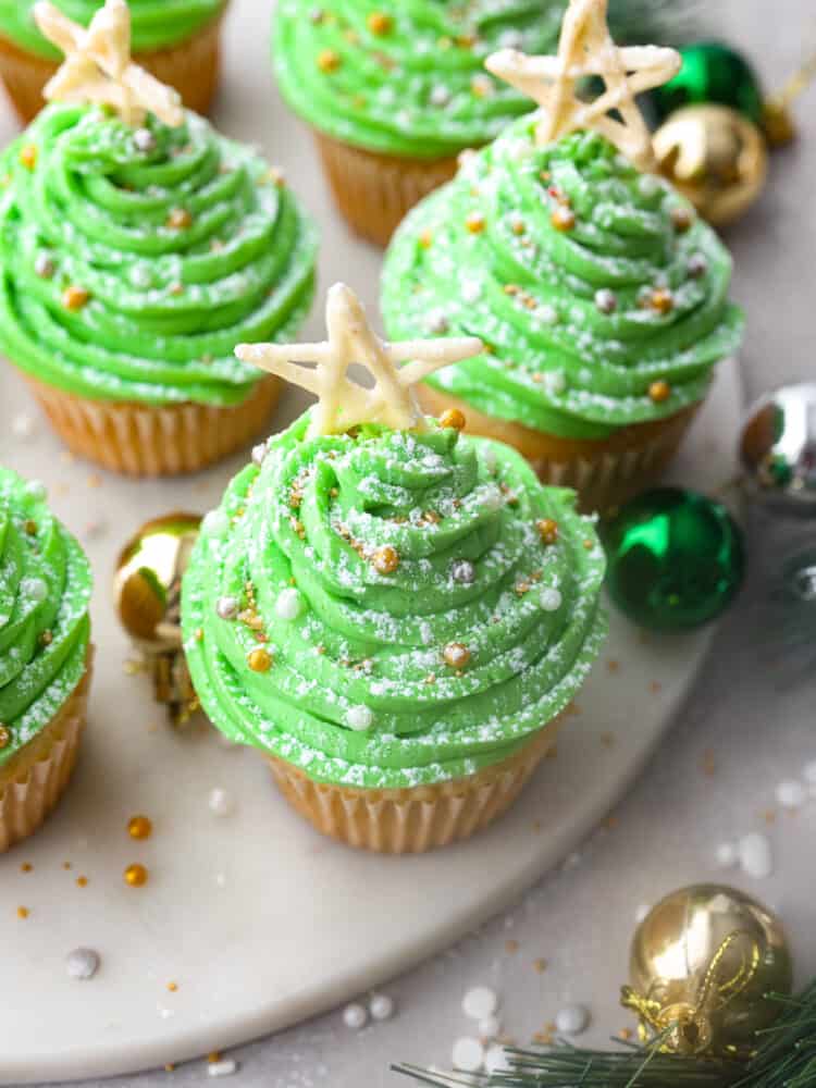 Top-down view of Christmas tree cupcakes, garnished with sprinkles and a pretzel star.