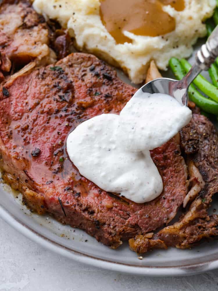 Sauce being put on top of a steak.