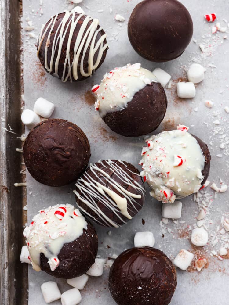 Top-down view of hot cocoa bombs laid out on a baking sheet lined with parchment paper.