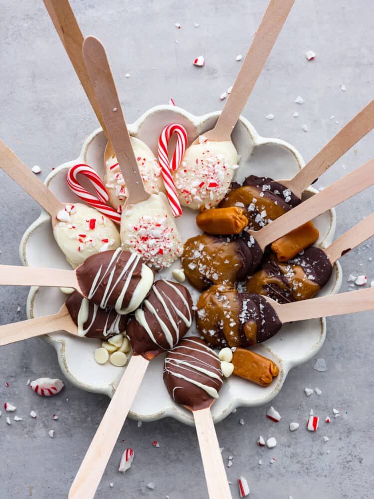 Various hot chocolate spoons served on a white dish.