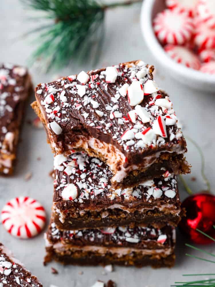 A stack of 3 brownies. One has a bite taken out of it.