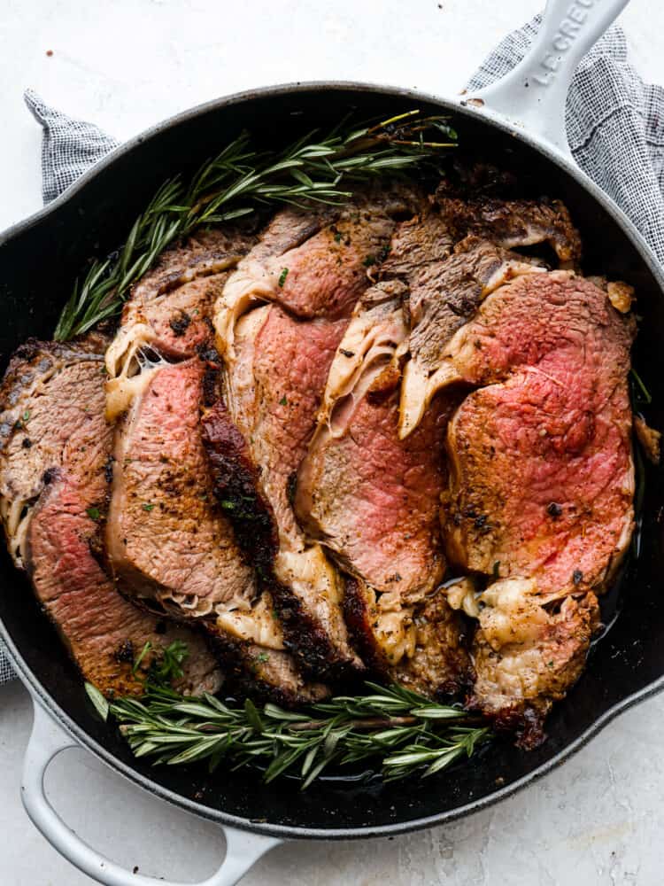 Top-down view of sliced prime rib in a skillet.