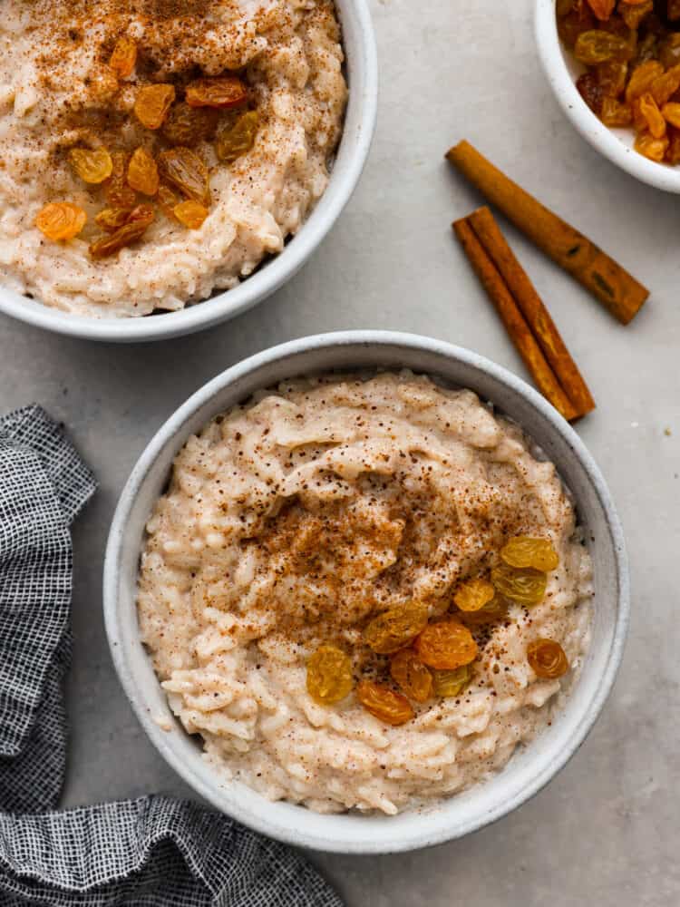 Top-down view of rice pudding served in white bowls with raisins as a garnish.