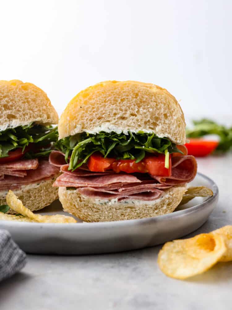 A picture of the sandwich on a plate with potato chips next to it.