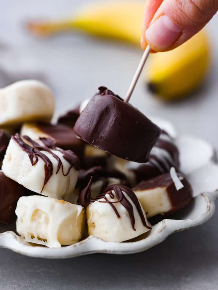 Picking up a chocolate covered banana with a toothpick.