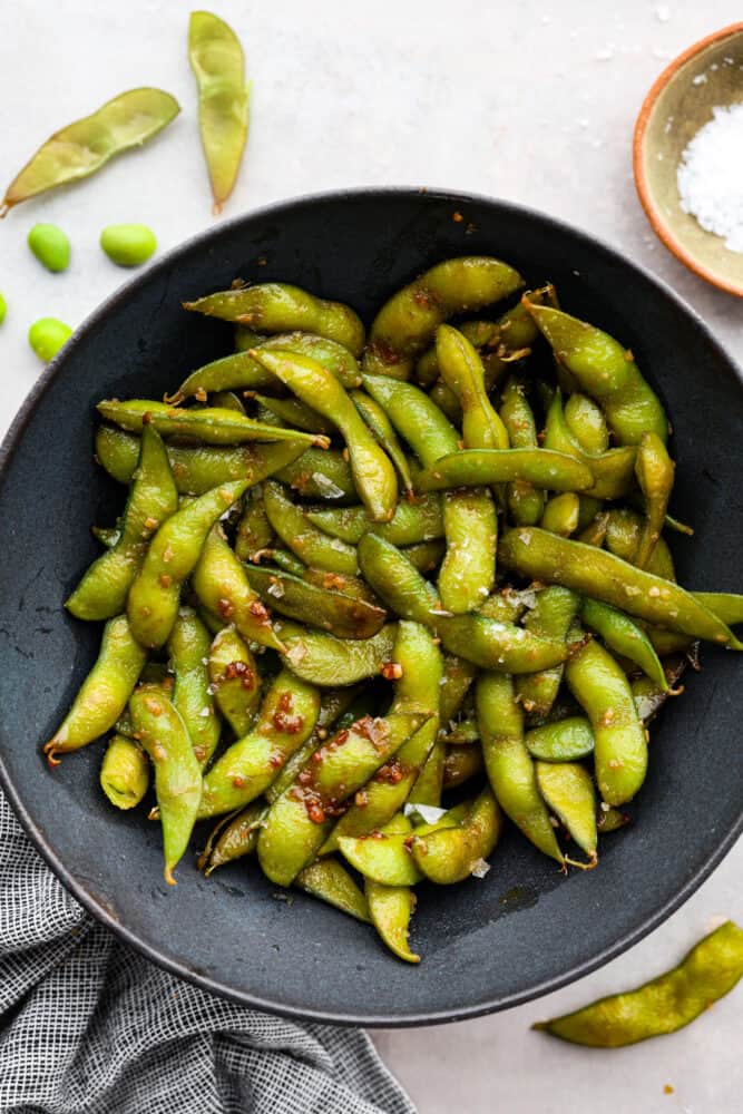 Top-down view of edamame served in a black bowl.