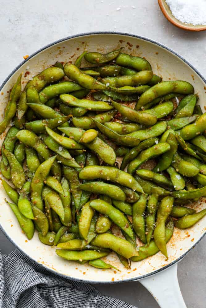 Garlic edamame in a blue and white skillet.